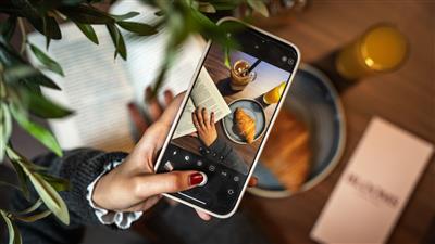 A woman taking a social media photo of a book and breakfast Blooms Coffee and Pizza