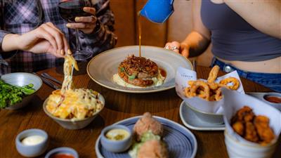 A platter of food on a table with a group of people preparing to eat at The London Pub 