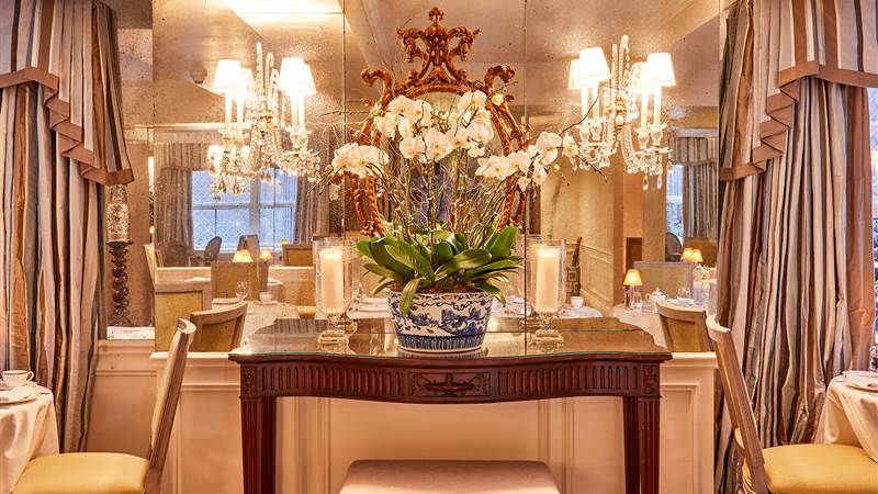 a formal dining area with a large floral arrangement and chandeliers