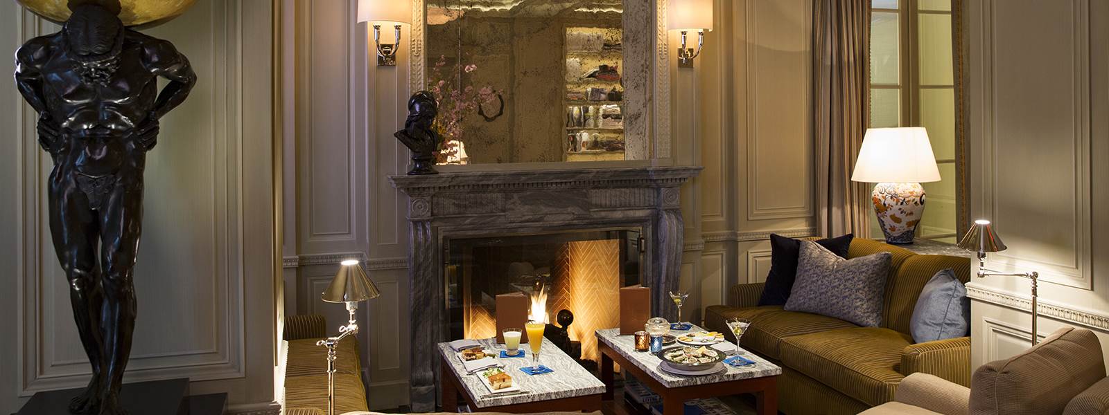 A luxurious lounge with a fireplace, seating area, and decorative statue.