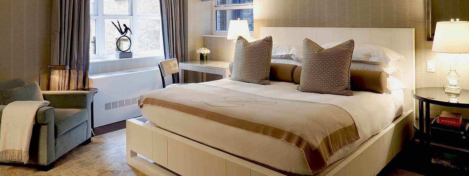 A neatly arranged hotel room with a large bed, comfortable chair, and desk by the window.